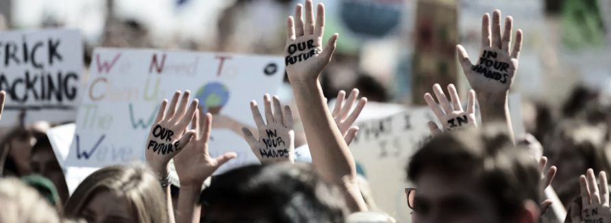 Arms raised in protest at a rally. Our future in your hands is written on many people's hands.